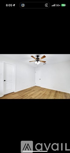 A room with a ceiling fan and wooden floor.