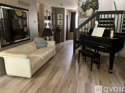 A living room with a white couch and a black piano.
