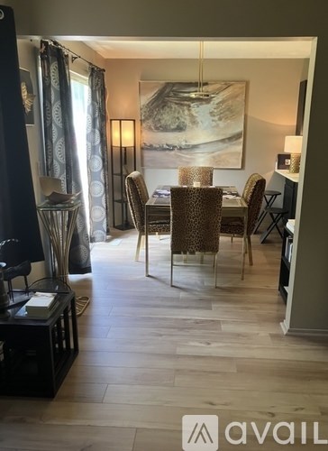 A dining room with a table set for two and a painting on the wall.