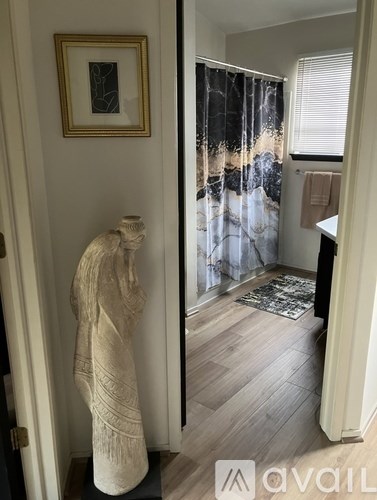 A room with a statue and a framed picture on the wall.