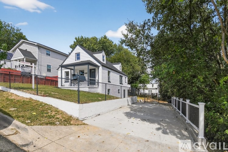 A house with a white fence and a driveway in front.