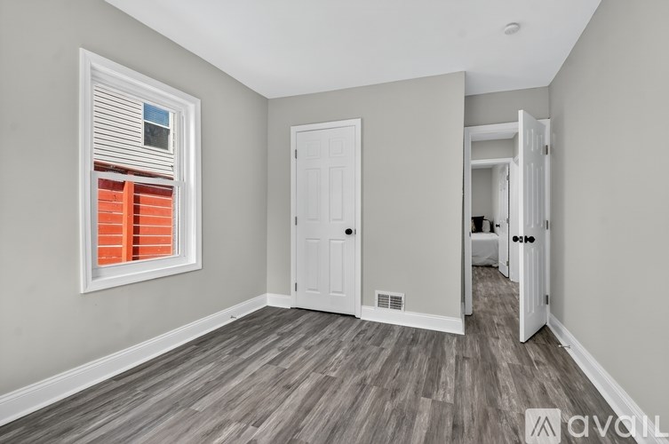 A room with a white door and a window with red blinds.