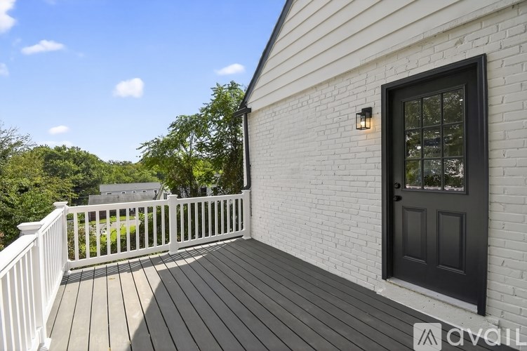 A white house with a black door and a wooden deck.