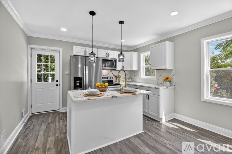 A modern kitchen with a white island and stainless steel appliances.