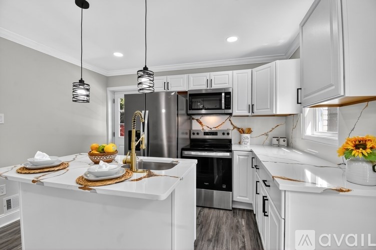 A modern kitchen with a white countertop and stainless steel appliances.