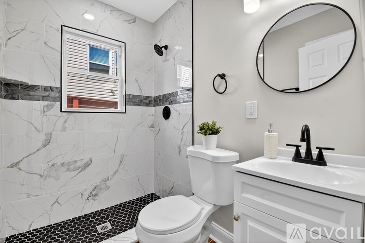 A bathroom with a toilet, sink, and a round mirror.