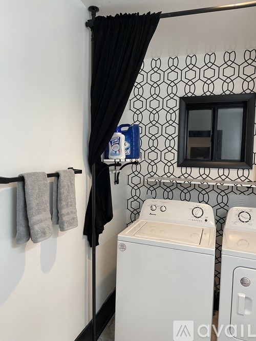 A small bathroom with a white washing machine and a black curtain.