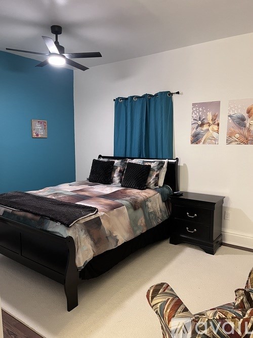 A bedroom with a bed, nightstand, and a ceiling fan.