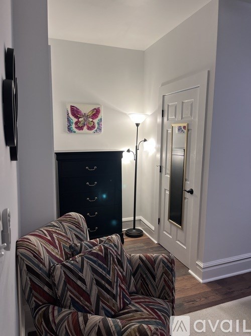 A butterfly picture hangs on the wall above a black dresser.