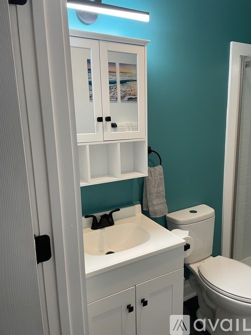 A white bathroom cabinet with a mirror above the sink.