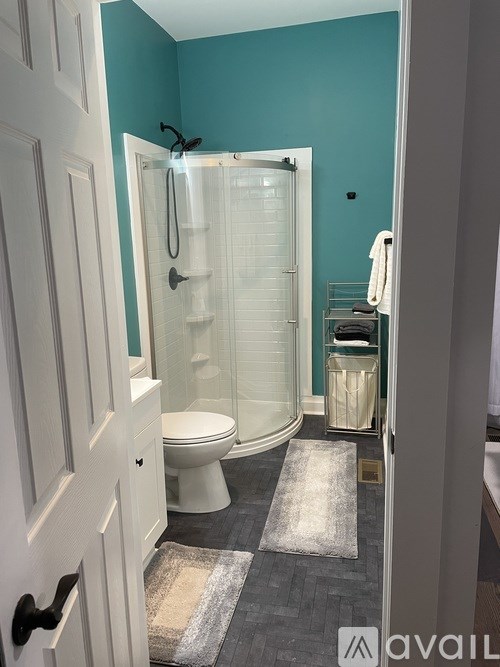 A bathroom with a toilet, a walk in shower, and a towel rack.