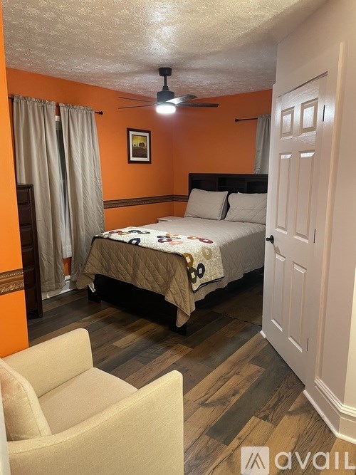 A bedroom with orange walls and a bed with a white comforter.
