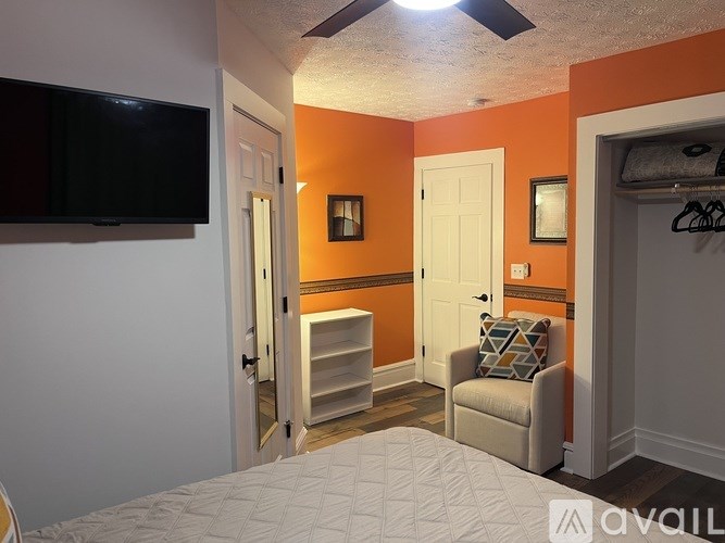 A bedroom with orange walls and a ceiling fan.