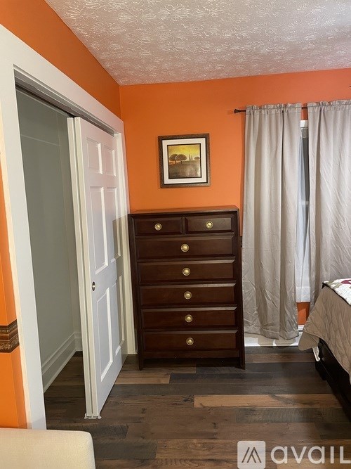 A bedroom with orange walls and a wooden dresser.