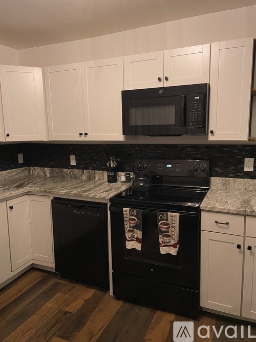 A kitchen with black appliances and white cabinets.