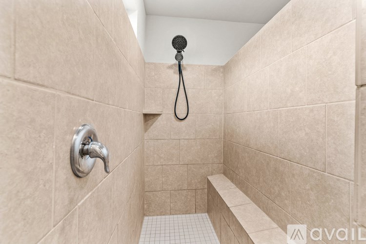 A bathroom with a shower head and a bench.