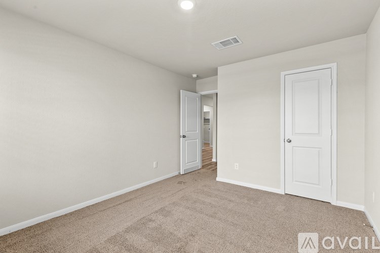 A room with white walls and carpeted floor with a door on the right.