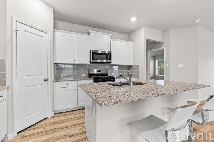 A kitchen with white cabinets and a granite countertop.