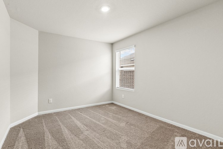 A room with a carpeted floor and a window with blinds.