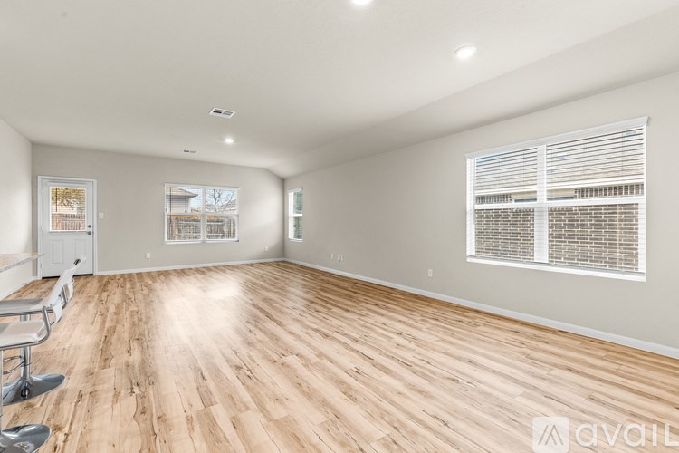 A room with wooden flooring and a window with blinds.