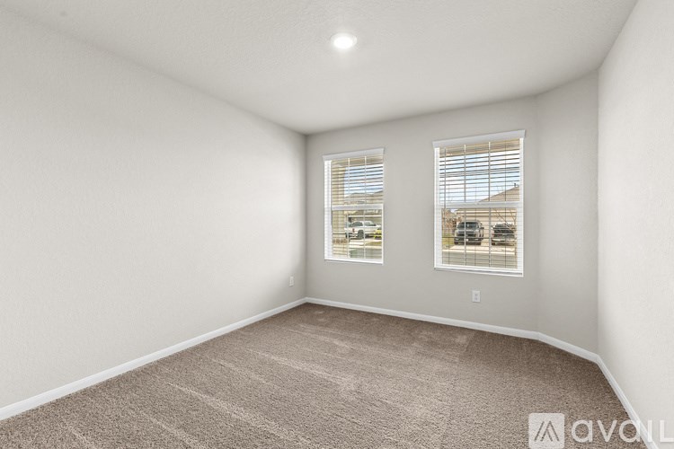 A room with carpeted floor and two windows.