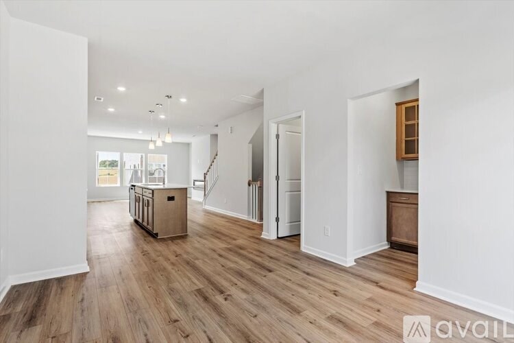 A spacious room with wooden flooring and white walls.