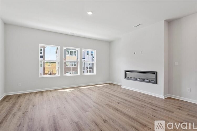 A spacious living room with wood flooring and a fireplace.