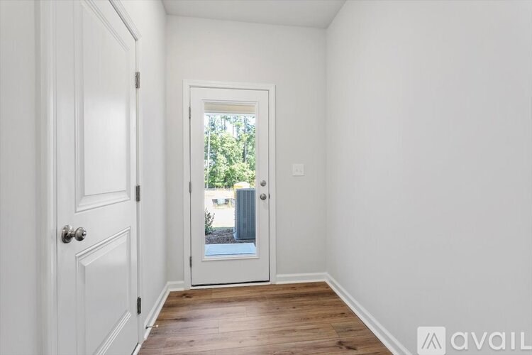 A white door with a glass window is in the middle of a hallway.