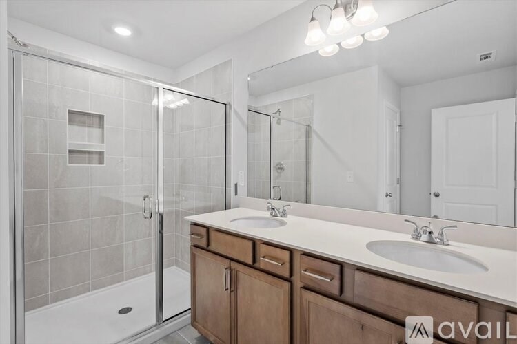 A bathroom with a walk-in shower and double sinks.