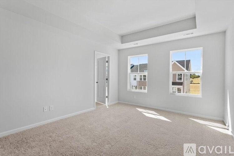 A room with a carpet floor and a window showing a view of a house.