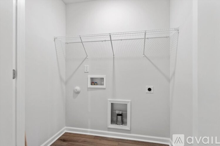 A white room with a hanging wire shelf and a small cabinet.