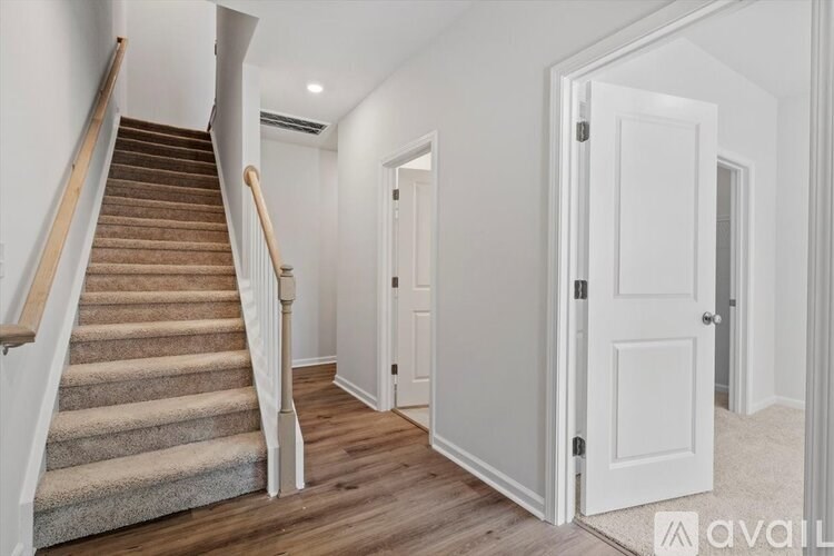 A staircase with a carpeted runner leads up to a landing with a white door.