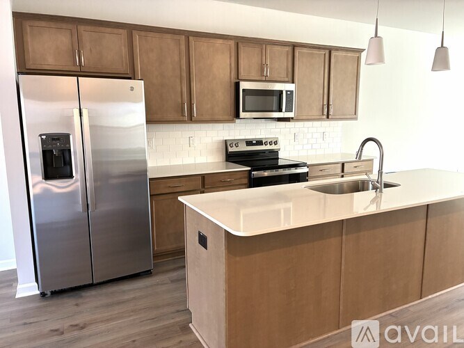 A kitchen with a stainless steel refrigerator, microwave, and a white countertop.