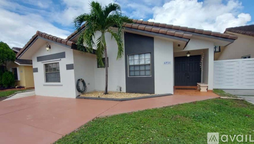 A house with a black door and a palm tree in front.
