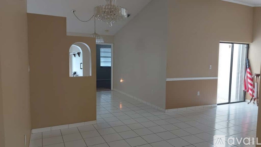 A room with a chandelier, a window, and a door.