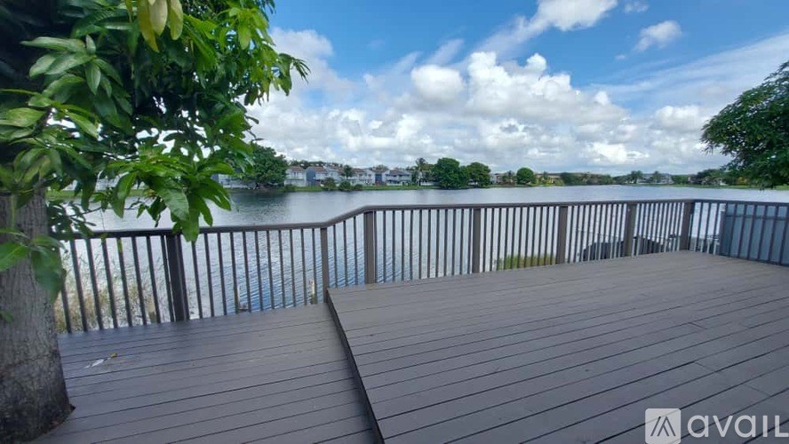 A wooden deck overlooks a body of water with a cloudy sky above.