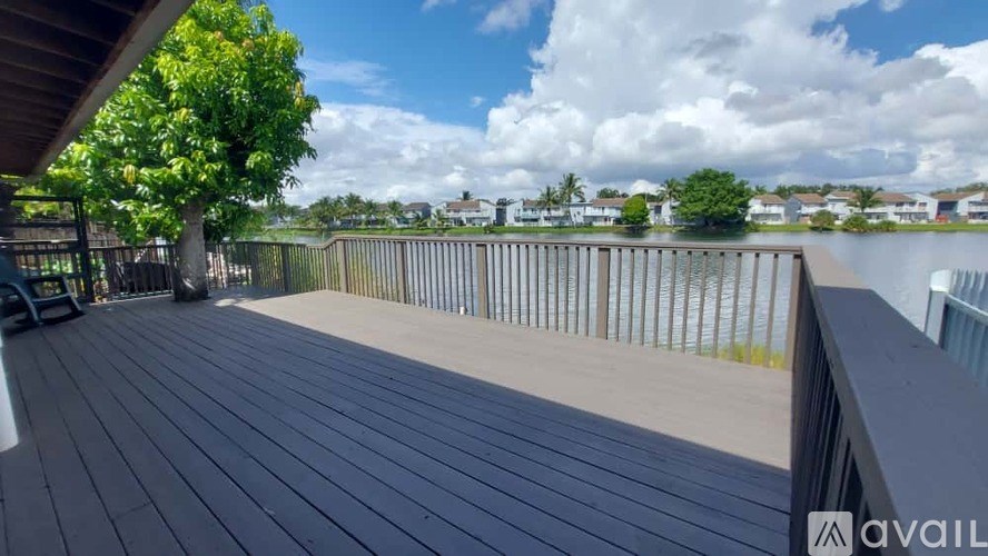 A wooden deck with a tree and a cloudy sky in the background.