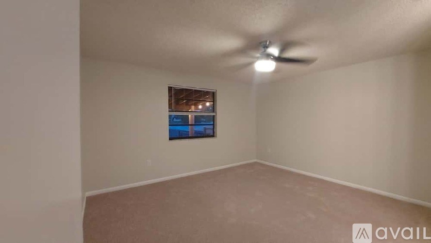 A room with a ceiling fan and a picture of a pool on the wall.