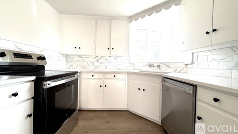 A kitchen with white cabinets and a black stove top oven.