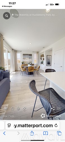 A modern living room with a dining area in the background.