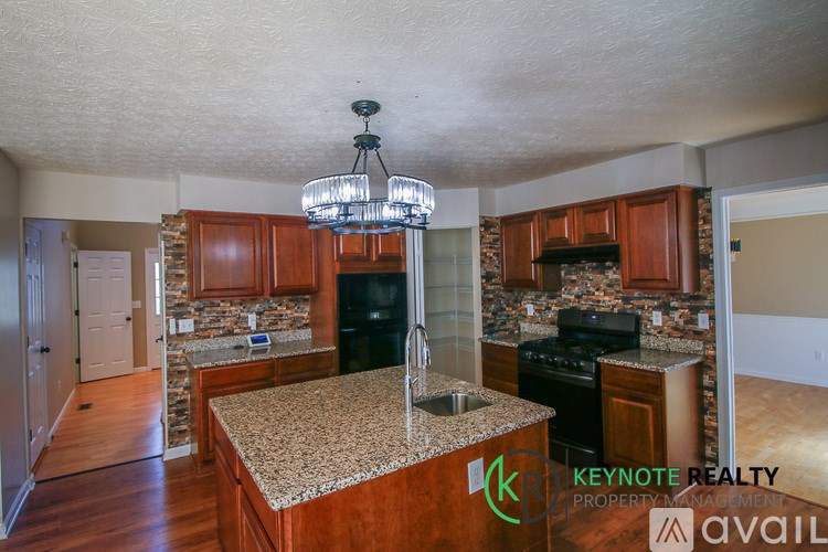 A kitchen with a granite countertop and wooden cabinets.