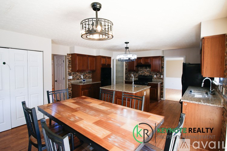 A kitchen with a wooden table and chairs in the foreground and a white door in the background.