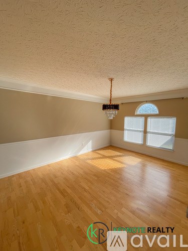 A room with wooden flooring and a chandelier hanging from the ceiling.