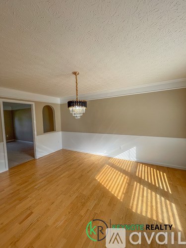 A room with wooden floors and a chandelier hanging from the ceiling.
