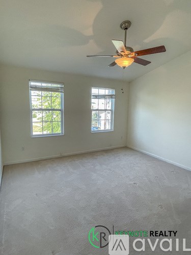 A room with a ceiling fan and two windows.