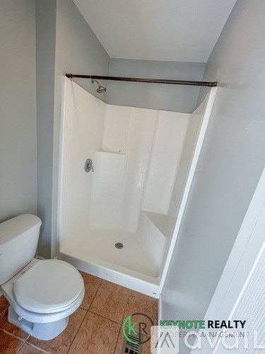 A white toilet sits next to a walk-in shower in a bathroom.
