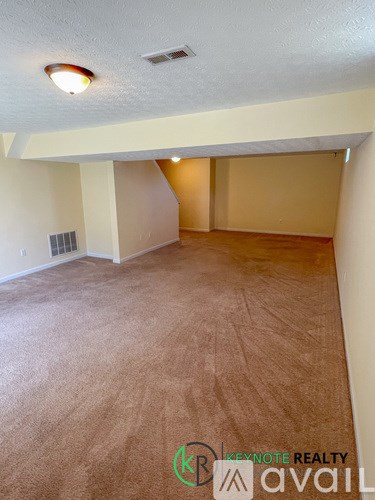 A room with a carpeted floor and a ceiling fan.