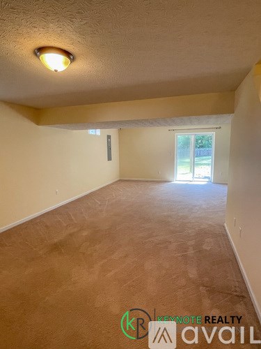 A room with a carpeted floor and a window letting in natural light.