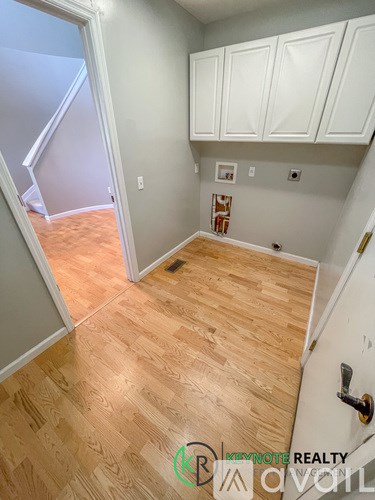 A room with wooden flooring and white cabinets.