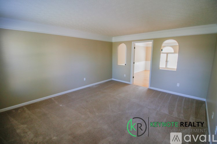 A room with a carpeted floor and two windows, one of which is open.
